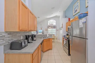 a kitchen with wooden cabinets and a stainless steel refrigerator at Cozy Private Home at Terra Verde Resort, South Facing Pool Spa, Near Disney, SeaWorld in Kissimmee