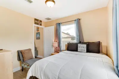 a bedroom with a bed and a window and a chair at 25 Mi to Disney Home with Shared Pool in Orlando in Orlando