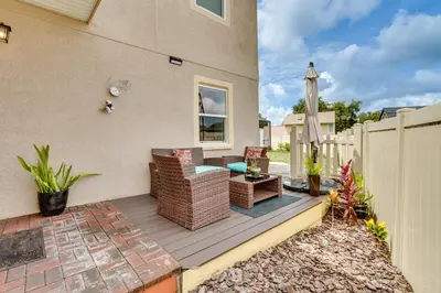 a patio with chairs and a table and an umbrella at 25 Mi to Disney Home with Shared Pool in Orlando in Orlando