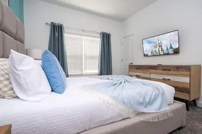 a white bed with blue pillows in a bedroom at Marvelous 4Bd with Pool at Storey Lake Resort 2601 in Kissimmee