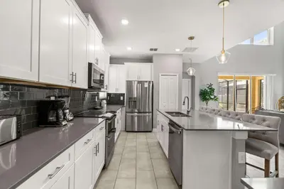 a kitchen with white cabinets and stainless steel appliances at Upstay Modern 5BR Resort Home w Pool & Hot Tub in Kissimmee