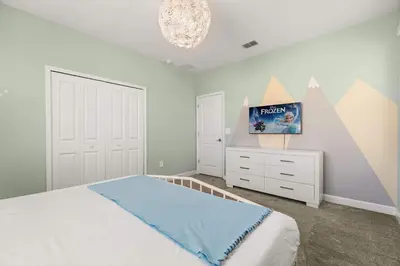 a bedroom with a bed and a dresser and a chandelier at Upstay Modern 5BR Resort Home w Pool & Hot Tub in Kissimmee
