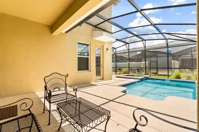 a patio with two chairs and a swimming pool at Upstay Modern 5BR Resort Home w Pool & Hot Tub in Kissimmee