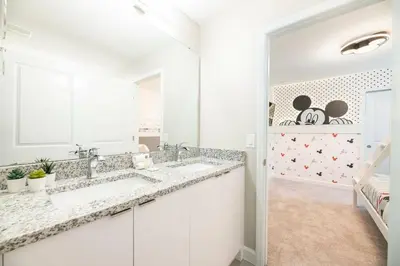a white bathroom with two sinks and a mirror at 7988 Magical 5BD Home Perfect Disney Retreat in Kissimmee