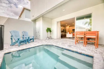 a swimming pool with two blue chairs and a table at 7988 Magical 5BD Home Perfect Disney Retreat in Kissimmee