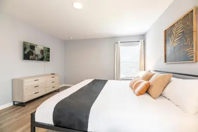 a white bedroom with a large bed and a dresser at Family Retreat 6BR Villa with Private Pool, Spa & Theater near Disney in Kissimmee