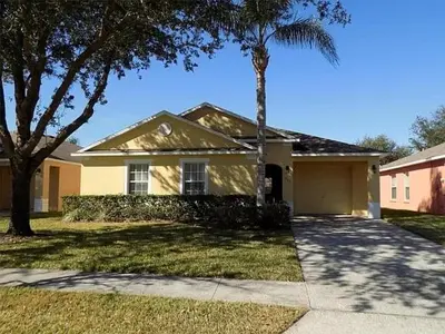 a yellow house with a palm tree and a driveway at 3 Bedroom Private Pool With Spa Near Disey villa in Orlando
