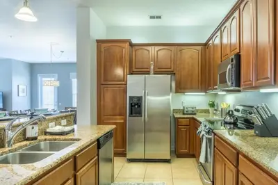 a kitchen with wooden cabinets and a stainless steel refrigerator at Penthouse Utopia condo in Orlando