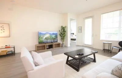 a living room with white furniture and a flat screen tv at NEW! Vista Cay Luxury Mirage condo in Orlando