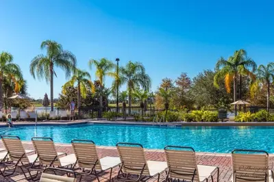 a pool with chairs and palm trees at NEW! Vista Cay Luxury Mirage condo in Orlando
