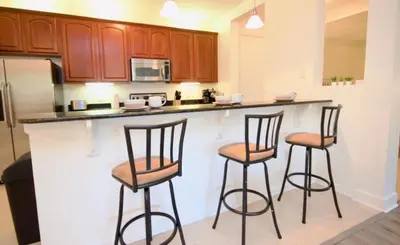 a kitchen with three bar stools in front of a counter at NEW! Vista Cay Luxury Mirage condo in Orlando