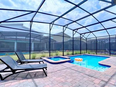 a swimming pool with a glass roof over a patio with two chairs at 8 Bed Storey Lake Resort- Huge Bedroom for Kids home in Kissimmee