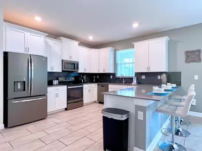 a large kitchen with white cabinets and a large island at 8 Bed Storey Lake Resort- Huge Bedroom for Kids home in Kissimmee