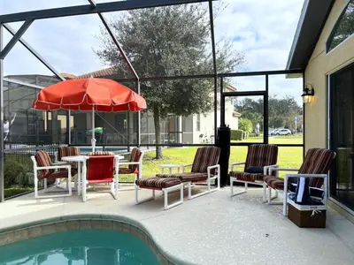 a patio with chairs and a table with an umbrella at Cozy 4 Bed 3 Bath Private Pool Home with Game Room home in Kissimmee