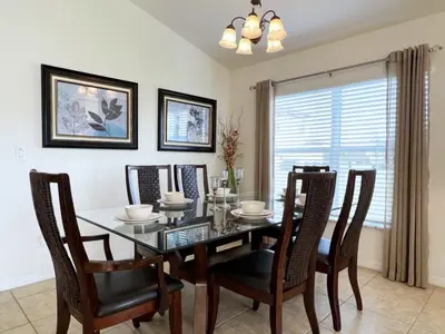 a dining room with a glass table and chairs at Cozy 4 Bed 3 Bath Private Pool Home with Game Room home in Kissimmee