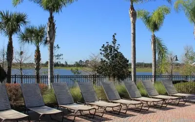 a row of lounge chairs sitting next to a body of water at Vista Cay Luxury Secret condo in Orlando