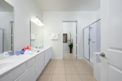 a white bathroom with two sinks and a mirror at Pool View Penthouse condo in Orlando