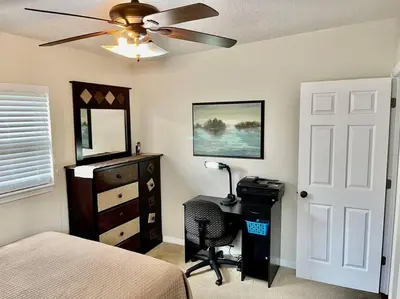 a bedroom with a bed and a desk and a ceiling fan at Cozy Modest Home near Universal Studios/VolcanoBay in Orlando