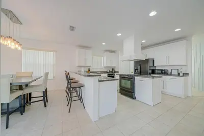 a kitchen with white cabinets and a table and chairs at 606 - Stunning 5 bed vacation rental home with private pool in Kissimmee