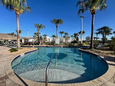 a swimming pool with palm trees in a resort at Spacious Home with Fun Decore and Game Room-4544TB in Kissimmee