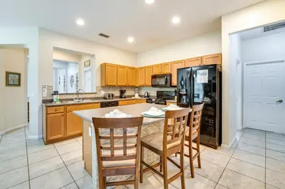 a kitchen with a table and chairs and a refrigerator at 10 Mi to Disney Home with Game Room and Lanai! in Kissimmee