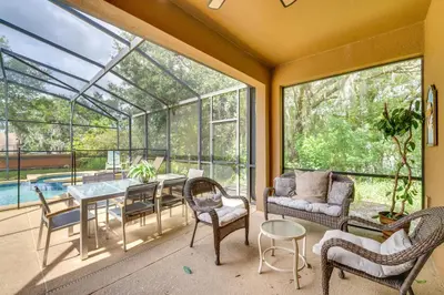a conservatory with a table and chairs and a dining room at 10 Mi to Disney Home with Game Room and Lanai! in Kissimmee