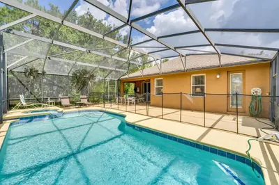 a swimming pool with a glass roof and a house at 10 Mi to Disney Home with Game Room and Lanai! in Kissimmee