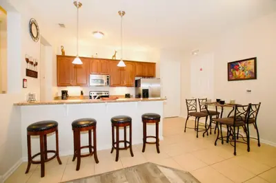 a kitchen with a bar with chairs and a table at Vista Cay Luxury Loft in Orlando