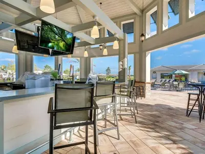 a patio with chairs and a bar with a flat screen tv at Cozy Condo Only 6 Minutes From Disney World in Kissimmee