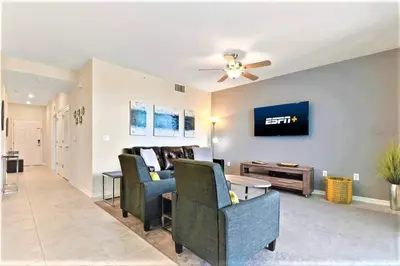 a living room with a couch and a tv on a wall at Cozy Condo Only 6 Minutes From Disney World in Kissimmee