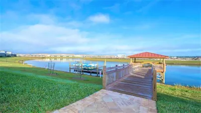 a wooden boardwalk leading to a dock on a lake at Relax in Ultimate Comfort with Pool & BBQ Area in Kissimmee
