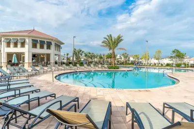 a resort pool with chairs and a building at Exquisite First-Floor Condo, 7 Min to Disney in Kissimmee