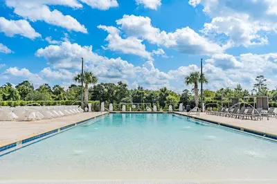 a large swimming pool with lounge chairs and palm trees at Sophisticated 4 En Suites w Private Hot Tub & BB in Orlando