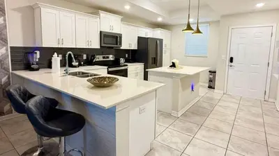 a kitchen with white cabinets and a counter top at Charming Holiday Condo, Only 7 min to Disney in Kissimmee