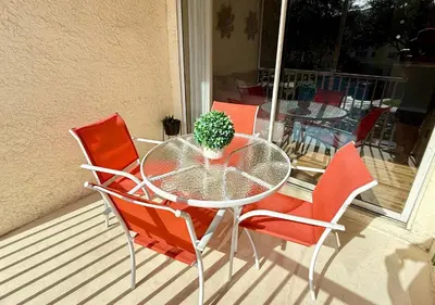 a glass table with red chairs and a potted plant at 2BR2BA Getaway 7 Miles from Orlando Parks in Kissimmee