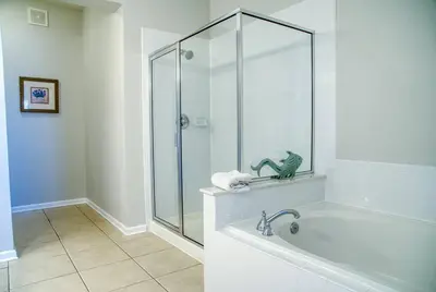 a bathroom with a shower and a bath tub with a green frog on a shelf at Vista Cay Luxury 3BR Condo in Orlando