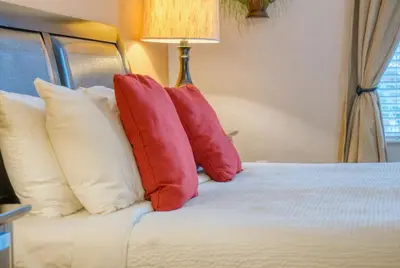 a bed with red pillows on top of it at Luxury Lake View Condo-Vista Cay in Orlando