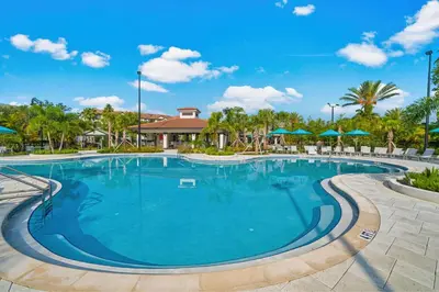 a large swimming pool at a resort with trees and umbrellas at Luxury Lake View Condo-Vista Cay in Orlando