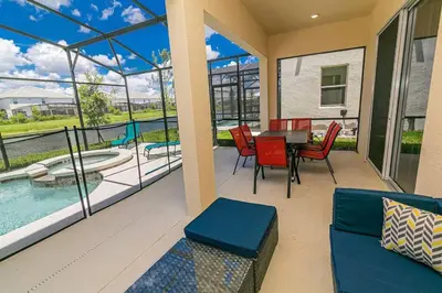 a patio with a table and chairs and a pool at ☀️12BR Disney Villa Paradise w/ Game Room & Pool/Spa☀️ in Kissimmee
