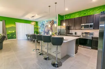 a kitchen with green walls and a bar with stools at ☀️12BR Disney Villa Paradise w/ Game Room & Pool/Spa☀️ in Kissimmee