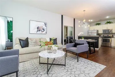 a living room with a couch and chairs and a kitchen at Modern Family-Friendly Townhome – 10 Min Parks in Kissimmee