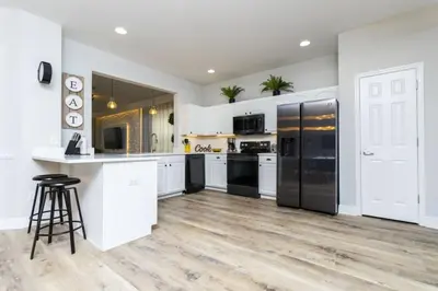 a kitchen with white cabinets and black appliances at Windsor Oasis 6BR Pool Game Room 9 min Disney in Orlando