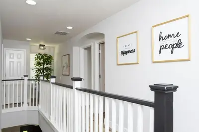 a hallway with white walls and stairs with two pictures on the wall at Windsor Oasis 6BR Pool Game Room 9 min Disney in Orlando