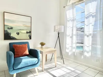 a living room with a chair and a table and a window at Beautiful 3BR House with Private Pool near Disney in Kissimmee