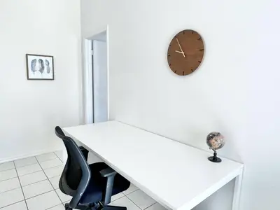 a white desk and a clock on a wall at Beautiful 3BR House with Private Pool near Disney in Kissimmee