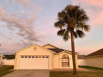 a palm tree in front of a house with a garage at Beautiful 3BR House with Private Pool near Disney in Kissimmee