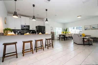 a kitchen and living room with a counter and chairs at Splendid 5Bd Close to Disney at Storey Lake 4251 in Kissimmee