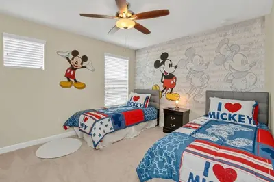 a bedroom with two beds and mickey mouse wallpaper at Near Disney - 5BR Home- Games Pool Hot Tub & BBQ in Kissimmee