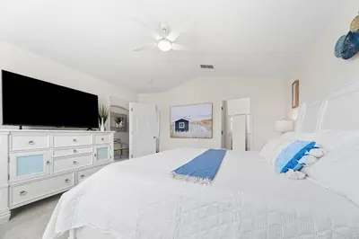 a white bedroom with a large bed and a flat screen tv at Private Oasis in Kissimmee - Pool, BBQ, Free Parking in Orlando