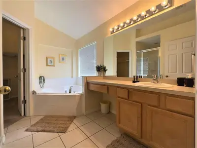 a bathroom with a tub and a sink and a bath tub at Restful 4BR 3BA with BBQ, Heated Pool & SPA in Kissimmee